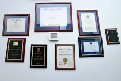 Dr. Daniels' accolades, awards, and degrees hanging on the wall at Smile Time Dentistry in DeSoto, TX